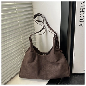Detail of dark brown suede tote bag featuring a magnetic clasp and adjustable strap
