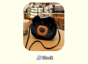 Close-up of black plush bear crossbody bag on a wooden table with a latte