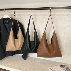 Détail de la texture tressée de trois grands sacs cabas en beige, noir et marron