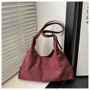 Close-up of matte burgundy faux suede hobo bag with adjustable silver buckle strap