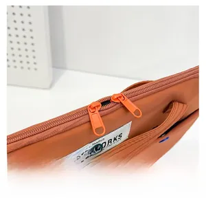 Détail de la double fermeture éclair fluide sur une housse d'ordinateur orange