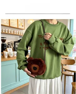 Close-up of a cute brown plush bear-shaped crossbody bag worn by a model in a cafe