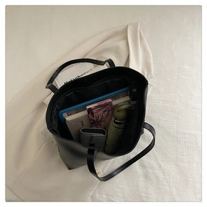 Spacious black leather tote bag showing internal storage for laptop and essentials