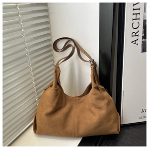 Close-up of matte camel suede hobo bag with stitched details in minimalist setting