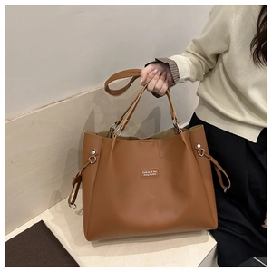 Dettaglio di una grande borsa tote marrone in finta pelle liscia con anelli in metallo