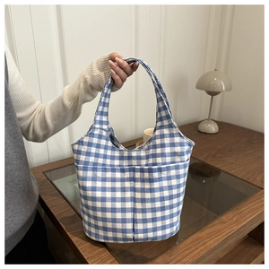 Detailed close-up of blue and white gingham tote bag with two front pockets on a table