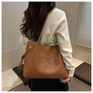 Dettaglio della borsa tote marrone in ecopelle con trama fine e decorazioni a nappe