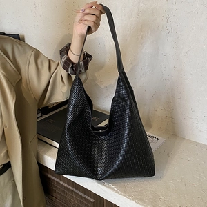 Détail du tressage complexe et du cuir noir brillant du sac à main de style Hobo