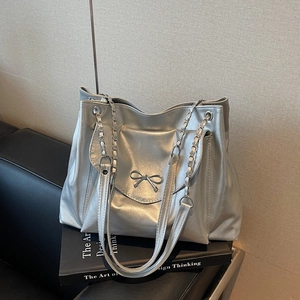 Gros plan du sac cabas argenté avec texture métallisée et détail de nœud chic