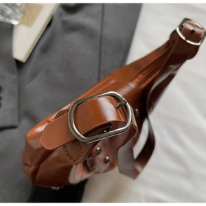 Detailed close-up of brown PU leather saddle bag with vintage silver metal buckle hardware