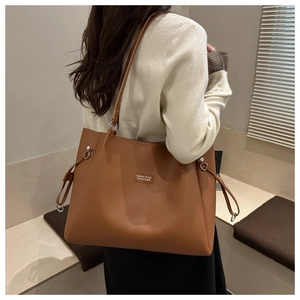 Dettaglio della borsa tote in pelle caramello con anello in metallo e etichetta