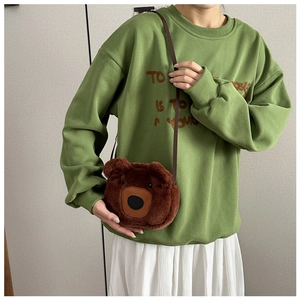 Detailed side view of the cute brown plush bear-shaped crossbody bag worn by a model