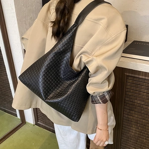Détail d'un sac cabas noir tressé en similicuir montrant la texture et la bandoulière