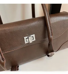 Close-up of the silver metal twist lock and dark brown faux leather texture of the handbag