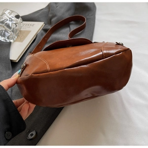 Detail view of the brown vintage saddle bag showing PU leather texture and curved shape