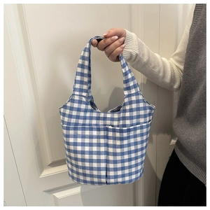 Detail showing blue and white checkered canvas bucket bag with functional front pockets