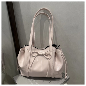 Detail of pink glossy leather tote with ribbon bow and elegant side drawstring textures