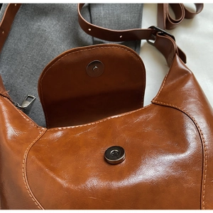 Detailed close-up of brown vintage saddle bag with magnetic closure and premium stitching