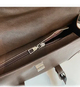 Detail view of the smooth silver zipper and interior structure of the dark brown bag