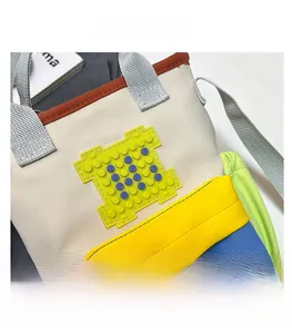 Detail shot of multi-color block canvas bag featuring block-style patch and gray handles