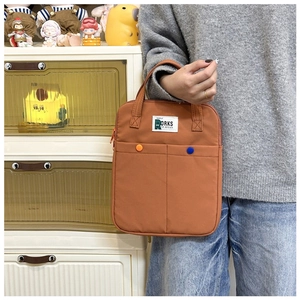 Gros plan sur un sac d'ordinateur marron avec poignées et boutons décoratifs