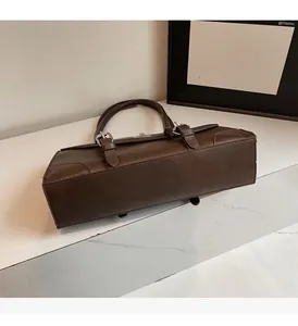Detail showing the dark brown matte leather texture and silver buckles of the shoulder bag