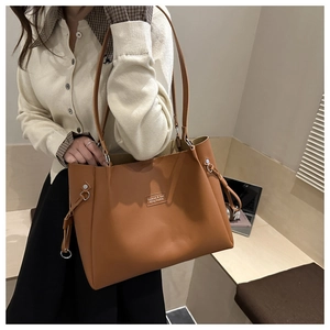 Dettaglio di una borsa tote in pelle marrone con coulisse laterali e anelli in metallo