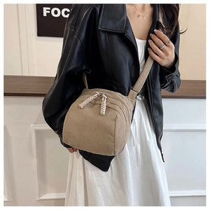 Detail of khaki corduroy shell bag with dual zipper and woven pulls on shoulder strap