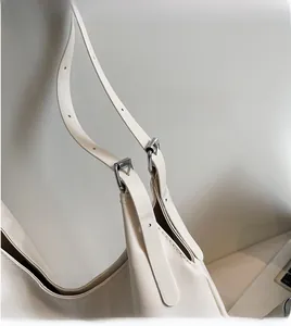 Detail of adjustable long shoulder strap with silver buckle on ivory tote bag