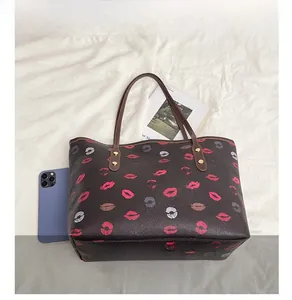 Detail of printed tote bag with lipstick patterns, long straps and gold metal rivets