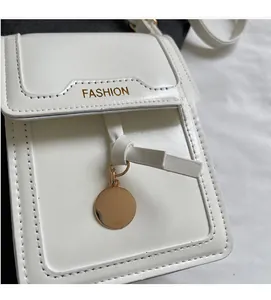 Λεπτομέρεια macro της λευκής τσάντας με χρυσό FASHION κείμενο και στρογγυλό μενταγιόν