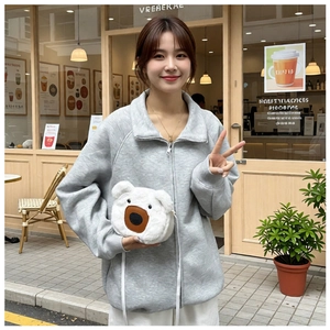Detail of soft white plush bear-shaped crossbody bag shown in an outdoor cafe setting