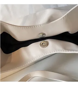 Detail view showing dual magnetic snap closures and silver hardware on a cream tote bag