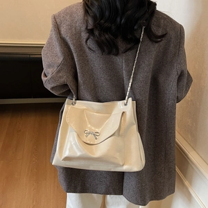 Détail du sac cabas crème avec boucle en métal et bandoulière en chaîne élégante
