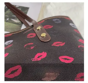 Close-up of golden metal rivets and lip print pattern on a high-quality tote bag
