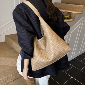 Détail d'un sac hobo tressé kaki montrant une grande capacité et un design minimaliste en similicuir