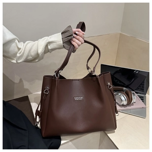 Dettaglio di una borsa tote in pelle marrone con fibbia ad anello e cinturino laterale