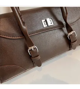Close-up of the vintage brown faux leather bag showing silver metal swivel lock and stitching