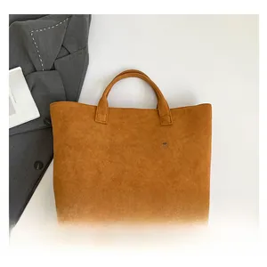 Makroaufnahme einer braunen Wildleder-Tragetasche mit weißem TOTE BAG-Schriftzug