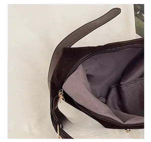 Detalle del bolso tote de ante marrón con cremallera metálica y correa ajustable