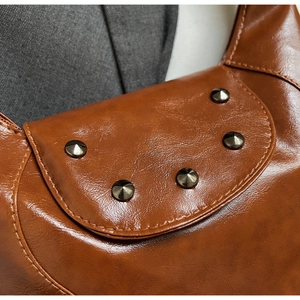 Detail of vintage brown saddle bag showing metal rivets and precise stitching on leather