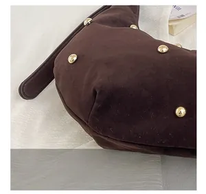 Detalle de bolso tote de ante marrón con remaches dorados y costuras de alta precisión