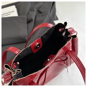 Close-up of red patent leather tote with magnetic clasp and delicate bow detail