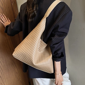 Vue latérale du modèle portant un grand sac cabas beige tressé en cuir PU de haute qualité