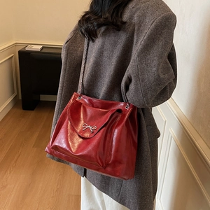 Sac à bandoulière rouge brillant avec nœud en métal argenté et bandoulière en chaîne