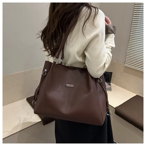 Borsa tote marrone scuro con finitura opaca e dettagli in metallo argento su modella