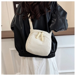 Detailed view of white corduroy shell bag with textured stripes and woven zipper pulls