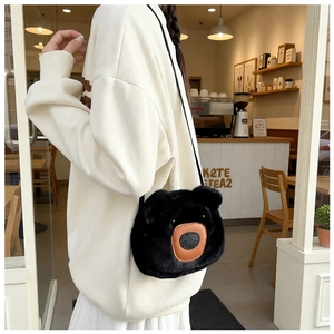 Close-up of soft black plush bear crossbody bag with detailed brown leather nose accent