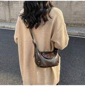 Detail of vintage dark brown saddle bag with silver studs and adjustable strap on a model
