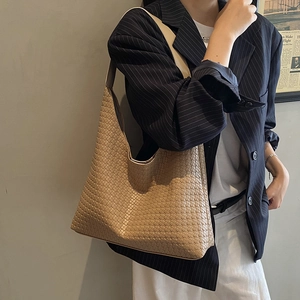 Vue détaillée du sac hobo beige avec texture tissée porté avec un costume rayé sombre